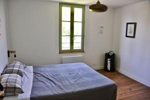 um quarto com uma cama com um edredão azul e uma janela em confortable maison familiale à l'entrée du village médiéval em Noyers-sur-Serein