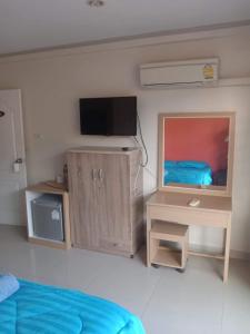a bedroom with a tv and a bed and a desk at Ban Por Fai in Cha Am