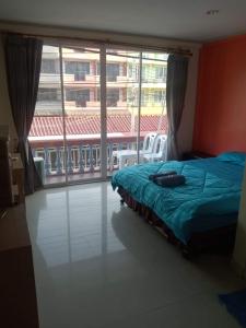 a bedroom with a bed and a large window at Ban Por Fai in Cha Am