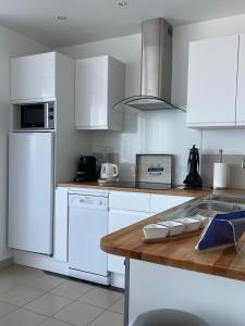 a kitchen with white appliances and a wooden counter top at Au Petit Brick - Cosy beachfront house in Maupertus-sur-Mer