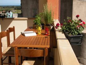un tavolo in legno con sedie su un balcone con piante in vaso di via dessi Orosei a Orosei