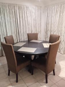einen schwarzen Tisch und Stühle in einem Zimmer mit Vorhängen in der Unterkunft East-Coast Guesthouse: Serene, Private, Secure in Durban