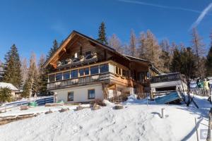 une maison en rondins dans la neige recouverte de neige dans l'établissement Bergblick, à Sirnitz