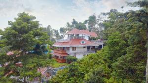 a large house with a red roof in the trees at Zenha Resorts in Munnar