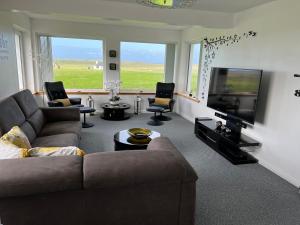 a living room with a couch and a flat screen tv at Tranquil Sands Holiday Home in Paible