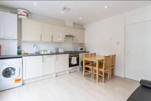 a kitchen with white cabinets and a table and chairs at Cozy 4 Bed Flat in Islington London in London