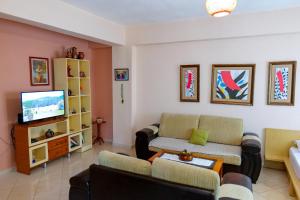a living room with a couch and a tv at Joyous Apartments in Sarandë