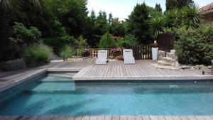 a swimming pool with two chairs on a wooden deck at Gîte du caveau in Marcorignan