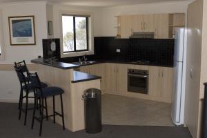 a kitchen with a refrigerator and a counter with stools at Cliff House Beachfront Villas in Moonta