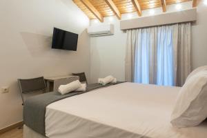 a bedroom with a large bed with a tv on the wall at OLYMPIA ROOMS in Myrina