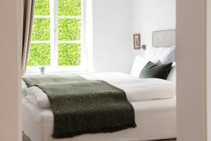 a bedroom with a white bed with a green blanket on it at Quartier 99 in Innsbruck