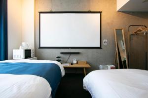 Zimmer mit 2 Betten und einem großen Bildschirm in der Unterkunft Theatel Haneda Ⅱ in Tokio