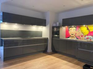 a kitchen with black cabinets and a painting on the wall at City Park Loft in Münchberg