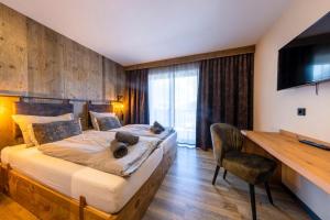 a bedroom with a bed and a desk and a television at Herz3 Hotel Bar Restaurant Trattoria in Hollersbach im Pinzgau