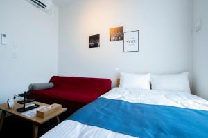 1 dormitorio con 1 cama y 1 sofá rojo en Theatel Haneda Ⅱ en Tokio