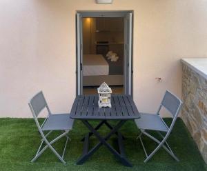 a picnic table with two chairs and a bedroom at OLYMPIA ROOMS in Myrina