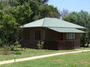 a small house with a tin roof in a yard at Riverbend Self Catering Cottages in Magaliesburg