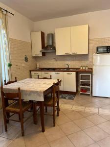 una cocina con mesa y algunos armarios blancos en Casa Vacanze Fraiese Vincenzo, en Paestum