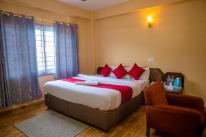 a bedroom with a large bed with red pillows and a chair at Hotel Yatri in Pokhara