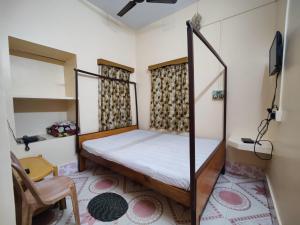 um quarto com uma cama e uma cadeira em Monalisa Lodge em Vishnupur