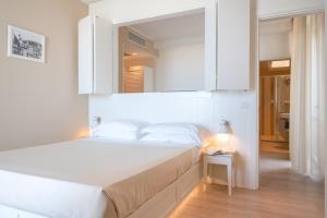una camera con letto bianco e specchio di Hotel Bristol a Cattolica