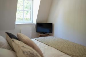 een slaapkamer met een bed en een flatscreen-tv bij Les Hirondelles, gîte de charme avec jardin, 7p in Saint-Valery-sur-Somme