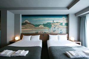 two beds in a room with a painting on the wall at Minn Ueno in Tokyo