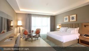 a hotel room with a bed and a desk at Grand Cosmopolitan Hotel in Dubai