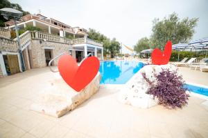 Due cuori rossi seduti su una roccia vicino a una piscina di Residence Il Falco a Vieste