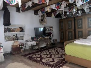 a bedroom with a bed and a tv and a table at Rustic Rooms in Ţopa