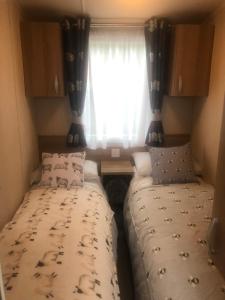 two beds in a small room with a window at Cosy holiday caravan minutes from the beach in Aberystwyth