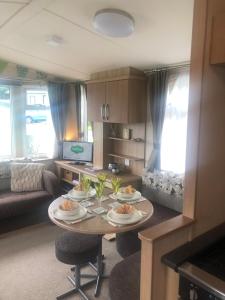 a kitchen and living room with a table with dishes on it at Cosy holiday caravan minutes from the beach in Aberystwyth