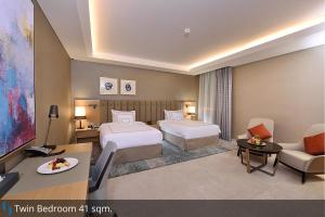 a hotel room with two beds and a television at Grand Cosmopolitan Hotel in Dubai