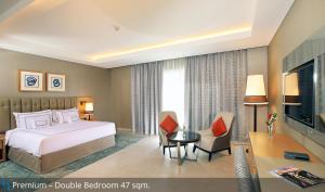 a bedroom with a bed and a desk and a television at Grand Cosmopolitan Hotel in Dubai