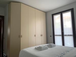een slaapkamer met een bed met witte lakens en een raam bij Appartamento rosada in Stresa