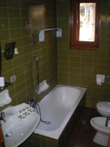 baño de azulejos verdes con bañera y lavamanos en Residence I Comignoli en Scanno
