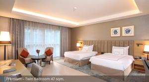 um quarto de hotel com duas camas e uma secretária em Grand Cosmopolitan Hotel em Dubai