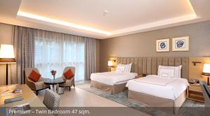a hotel room with two beds and a desk at Grand Cosmopolitan Hotel in Dubai