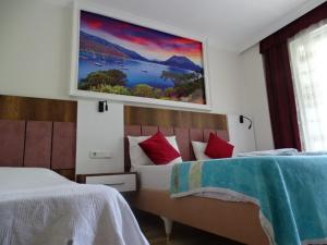 a bedroom with two beds and a painting on the wall at Arikanda River Garden Hotel in Adrasan