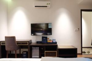 a bedroom with a desk and a tv on a wall at Aisha House and Apartment in Hanoi