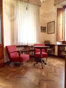 biblioteca con sillas rojas, mesa y ventana en Villa Puccini en Montecatini Terme