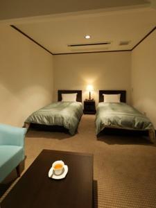 軽井沢町にあるホテルプティリヴィエール軽井沢のベッド2台、テーブル(食器付)が備わる客室です。