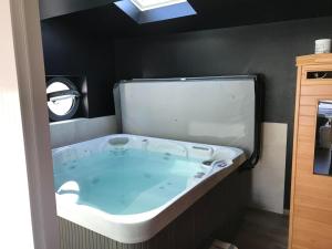 a bath tub in a bathroom with a black wall at Gîte spa sauna piscine in Aubin-Saint-Vaast
