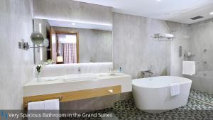 a bathroom with a tub and a large mirror at Grand Cosmopolitan Hotel in Dubai