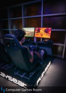 a man sitting in a gaming room with two monitors at Grand Cosmopolitan Hotel in Dubai