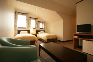 a hotel room with two beds and a tv at Hotel Petit Riviere Karuizawa in Karuizawa