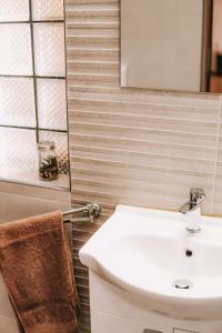 La salle de bains est pourvue d'un lavabo blanc et d'un miroir. dans l'établissement Cozy 2-Bedroom Boho-Themed Home, à Caransebeş