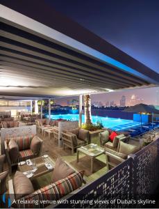 a restaurant with couches and tables and a pool at Grand Cosmopolitan Hotel in Dubai