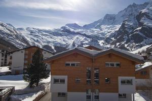 a building with snow covered mountains in the background at Chalet Haus Perla in Saas-Fee