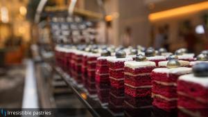 a row of red and white cakes on a shelf at Grand Cosmopolitan Hotel in Dubai